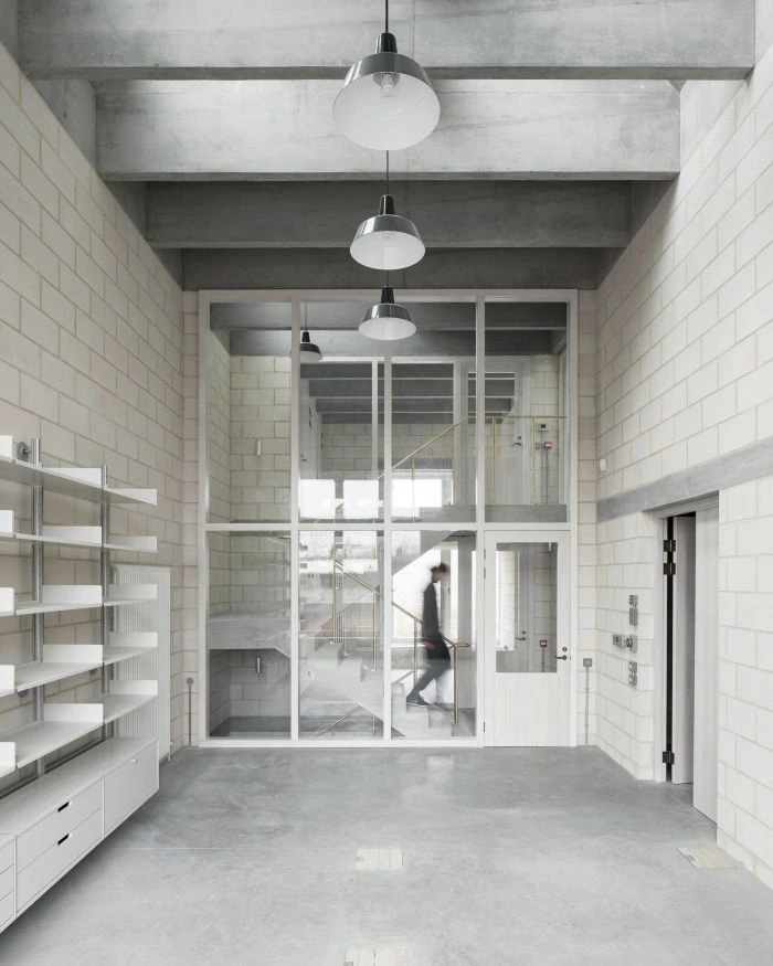 White internal glazed timber screen and door in an industrial interior, with a blurred person walking behind the glass.