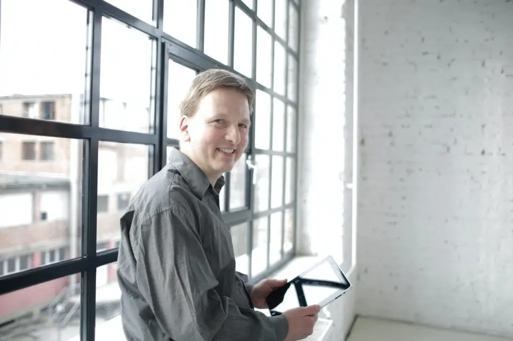Who sells timber windows? A timber window reseller in front of a large window in loft style office where he has the option to buy timber windows