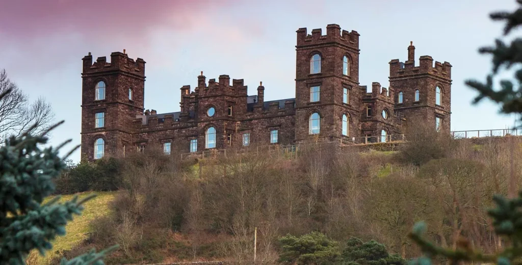 An impressive stone-built historic residence, part of the renowned Riber Castle estate in Matlock, featuring finely crafted heritage timber windows. The traditional sash-style glazing blends seamlessly with the building’s grand façade, illustrating how Gowercroft’s bespoke solutions preserve the architectural integrity and period character of one of Derbyshire’s most iconic heritage sites.